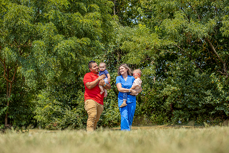 Man and woman in nurse scrubs carrying kids through a field