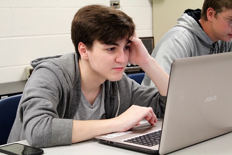 male student sitting in front of laptop