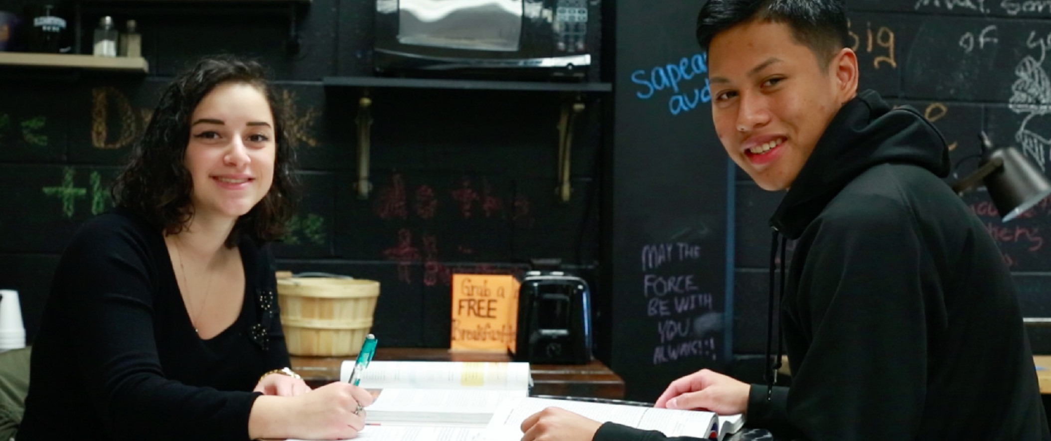 two people in coffee shop doing homework