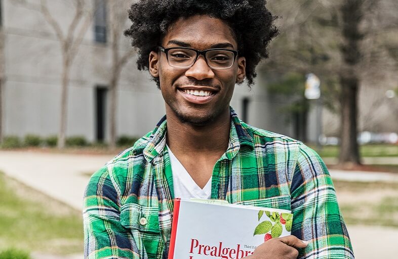 student smiling and holding textbook