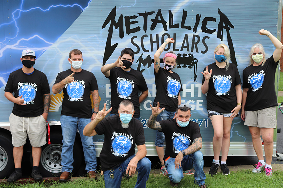 8 recipients of Metallica Scholars Scholarship standing in front of “Ride the Lightning Learning Lab” trailer