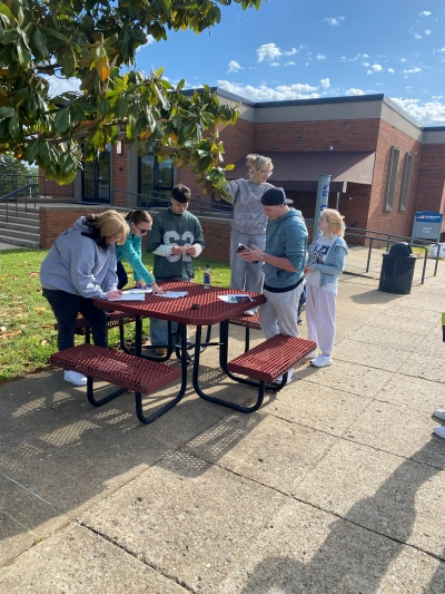 group of students outside at a picnic table while identifying trees