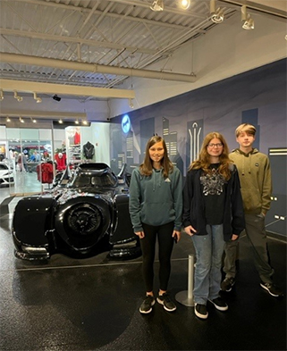 3 students in front of a black car