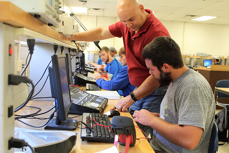 instructor showing student how to use electronic equipment 