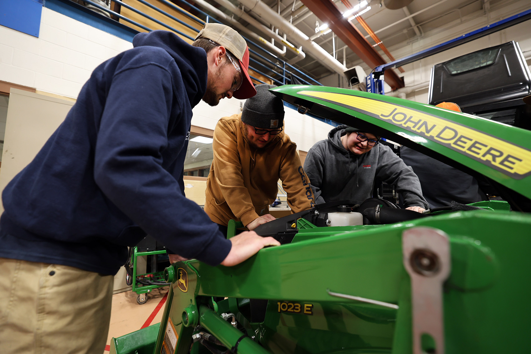 4 students around the open hood of a John Deere