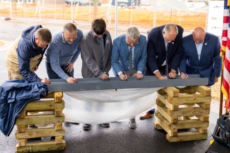 group of men, including the KCTCS President and ECTC President, signing a structural beam